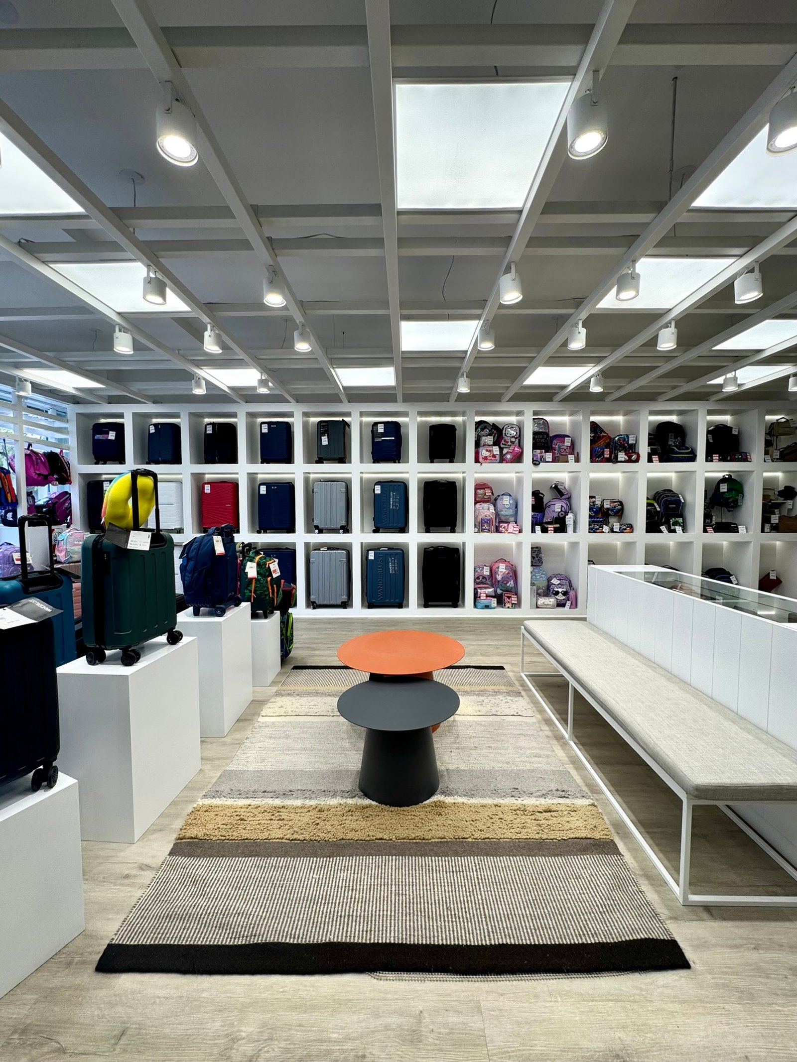 Tienda de equipaje con alfombra geométrica y mesa redonda — proyecto Leonardo Marroquinería, por MDBK Arquitectura, en Balvanera