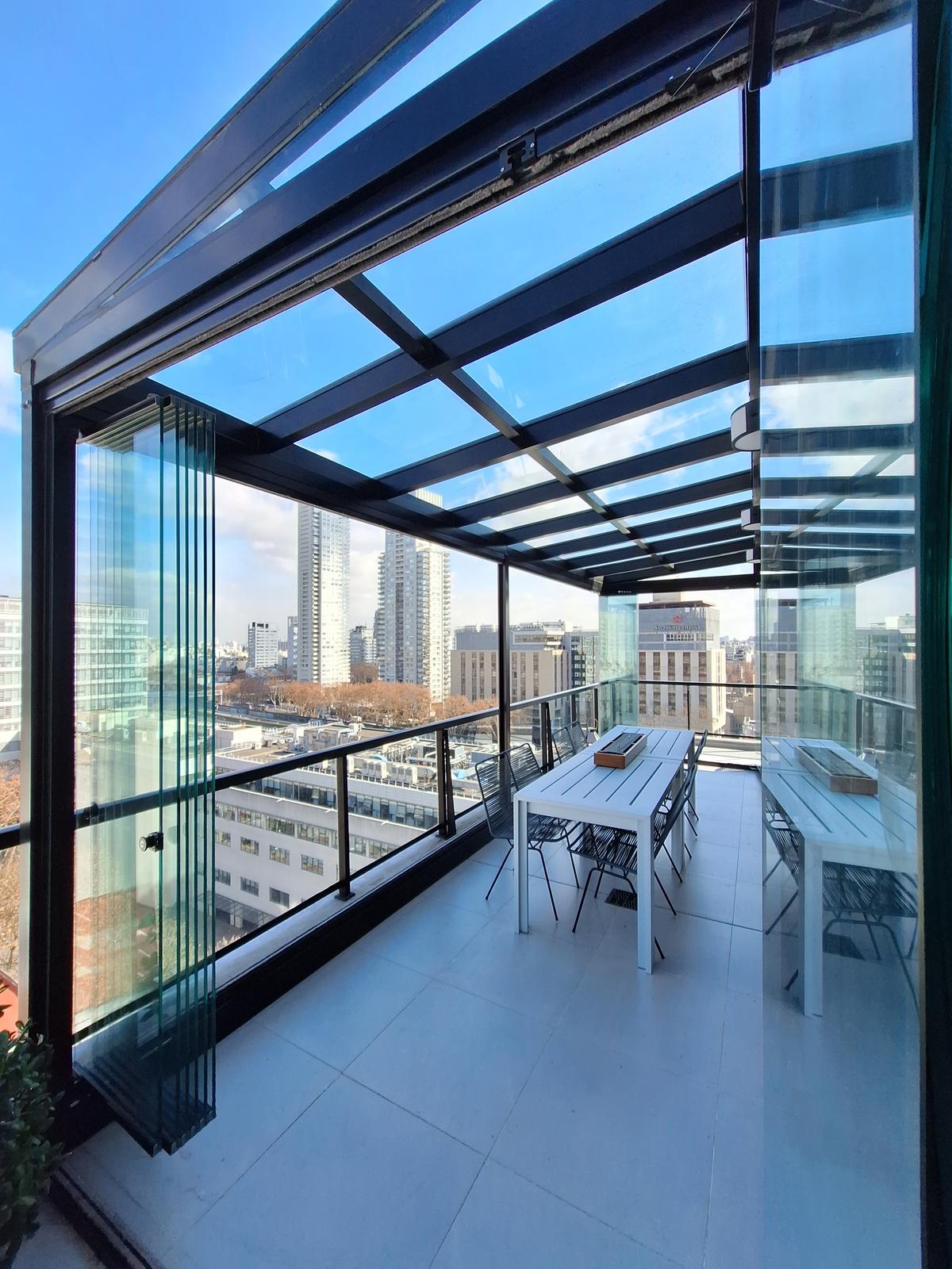 Terraço moderno envidraçado com vista urbana e mesa de jantar — projeto TOLDER - CERRAMIENTOS, por Argentina en Obra 2024, em Rincón de Milberg