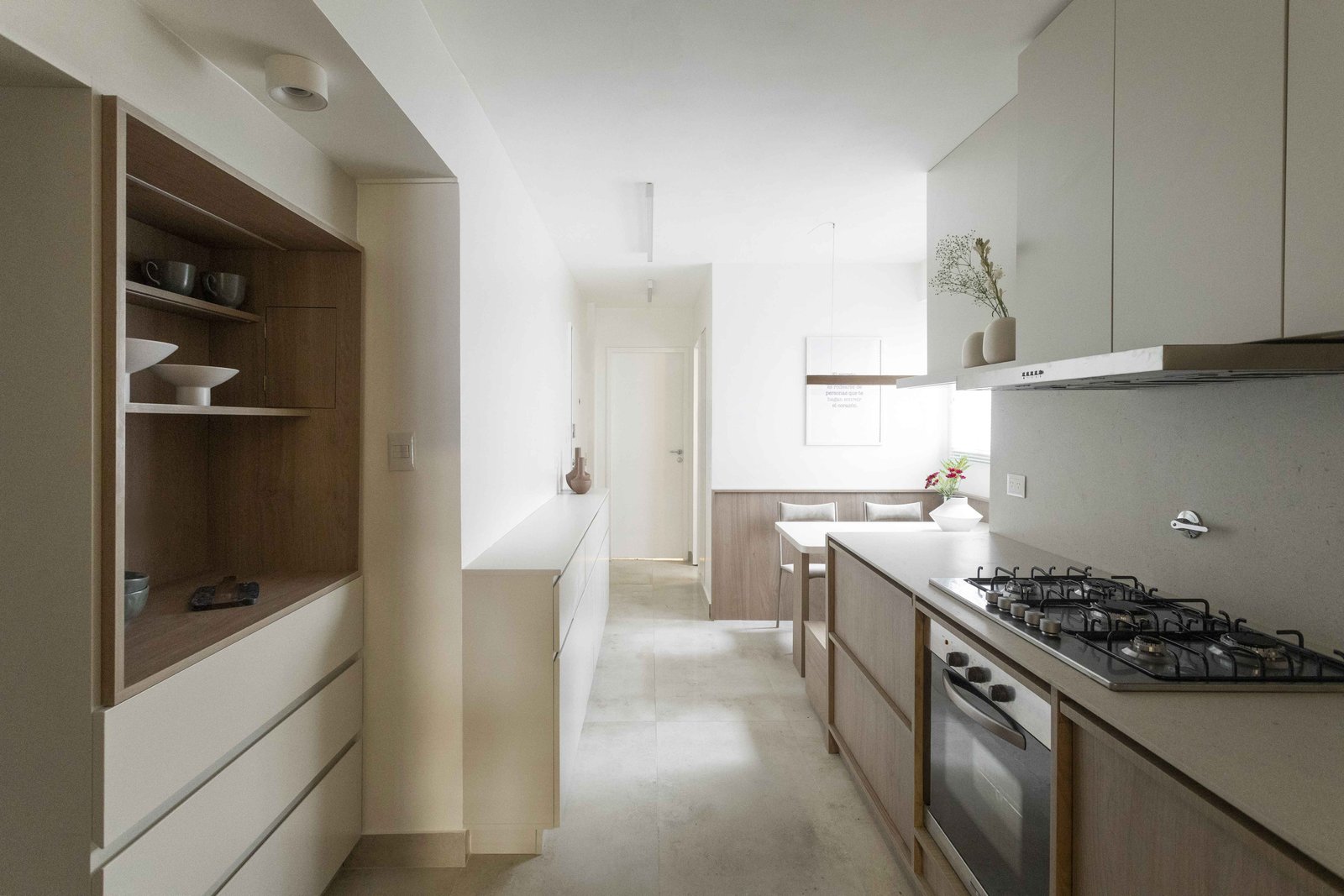 Cocina minimalista moderna con comedor integrado y almacenamiento de madera — proyecto Libertador, por Bouré Studio, en Palermo