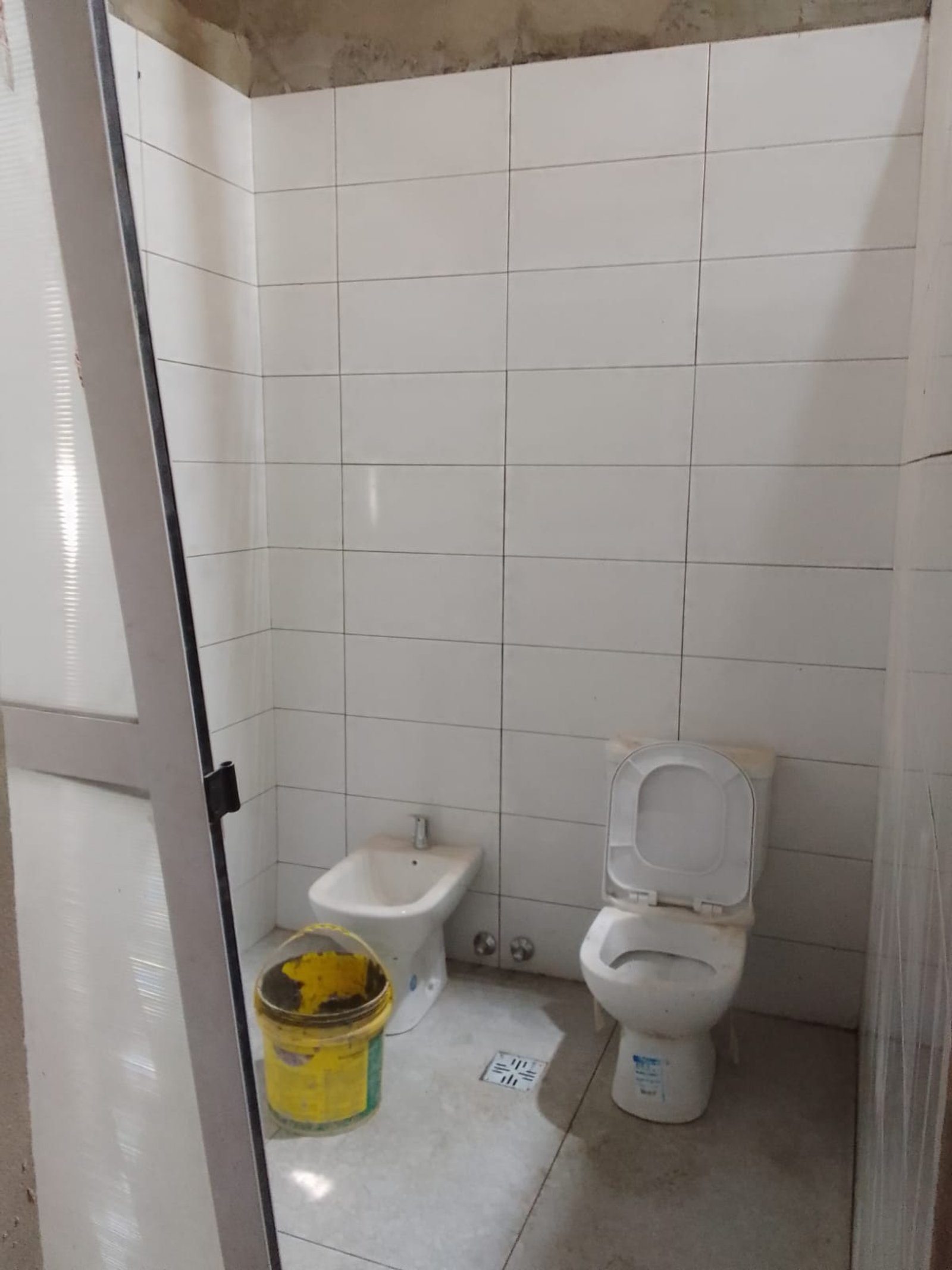 Baño con bidet, inodoro y balde amarillo — proyecto Deposito en Avellaneda 2, por Arquitecto Guido Niccoli, en B1872 Sarandí