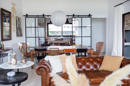 Living moderno con sillón de cuero, ventanal industrial y vista al exterior — proyecto JI 103, por Estudio Diez Muzzio