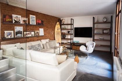 Living comedor industrial con ladrillo expuesto y sofá blanco modular — proyecto Defensa, por Estudio Basa, en CABA