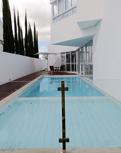 Pileta rectangular moderna en patio minimalista con pérgola y deck — proyecto Casa em Garanhuns Pernambuco, por André Caricio