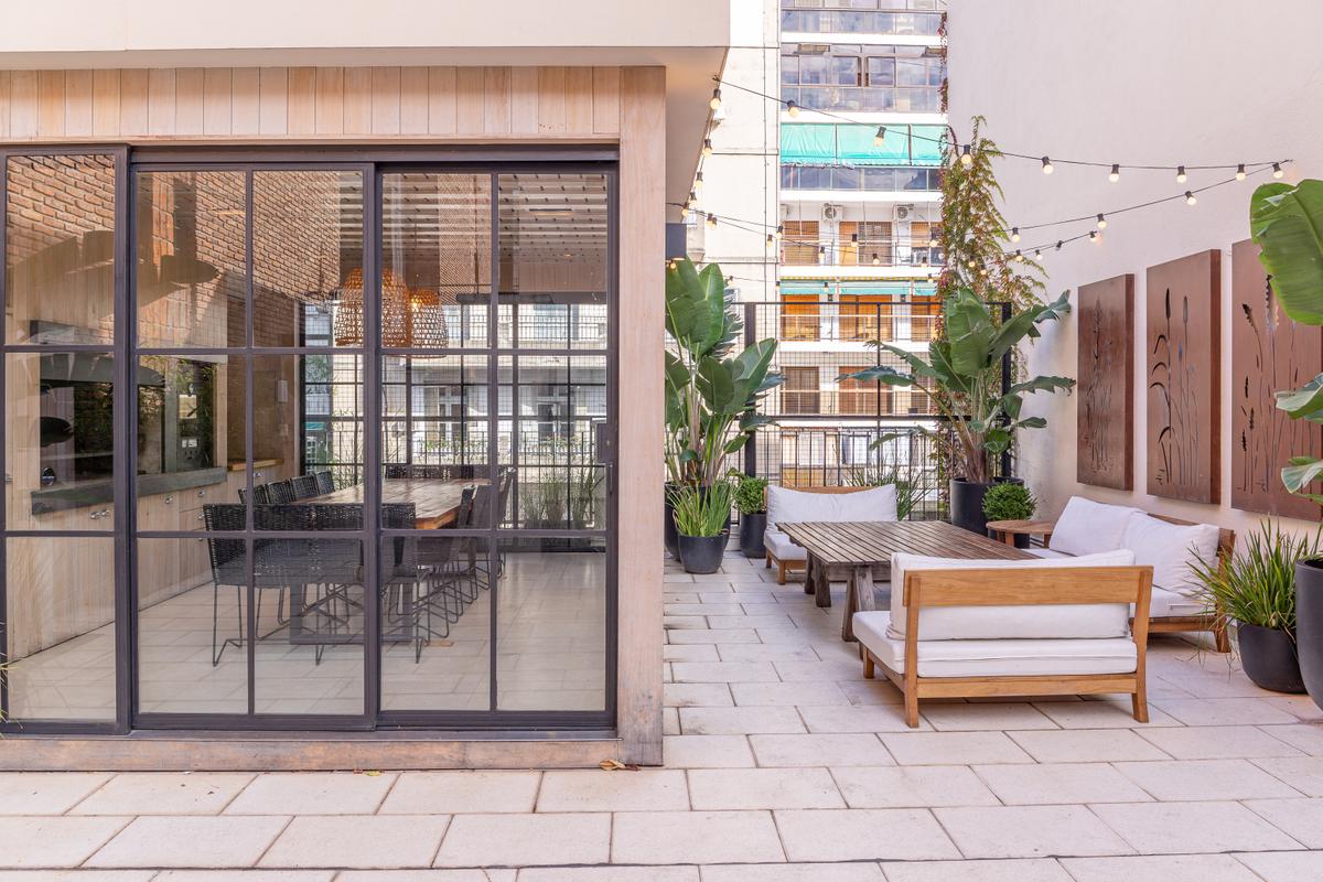 Área externa moderna com deck de madeira, pergolado e grandes janelas — projeto Terraza en la ciudad, por Casa Cunia, em CABA