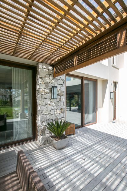 Terraza moderna con pergola de madera, deck gris y acceso vidriera — proyecto PGC-01, por VGLA Arquitectos, en General Pacheco