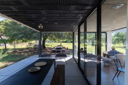 Galería moderna con vista al jardín, parrilla integrada y aberturas vidriadas — proyecto Casa SI, por Grupo Studio, en Villa Allende