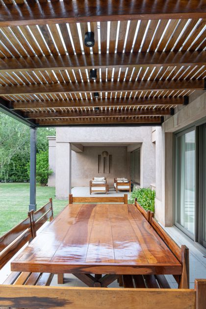 Terraza con pergola de madera, deck y vista al jardín verde — proyecto CASA EE, por Casa Cunia