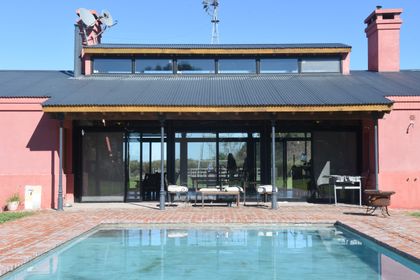 Pileta frente a casa contemporánea con fachada terracota y vidrios — proyecto Chacras del Parana, por Rioja Arquitectura