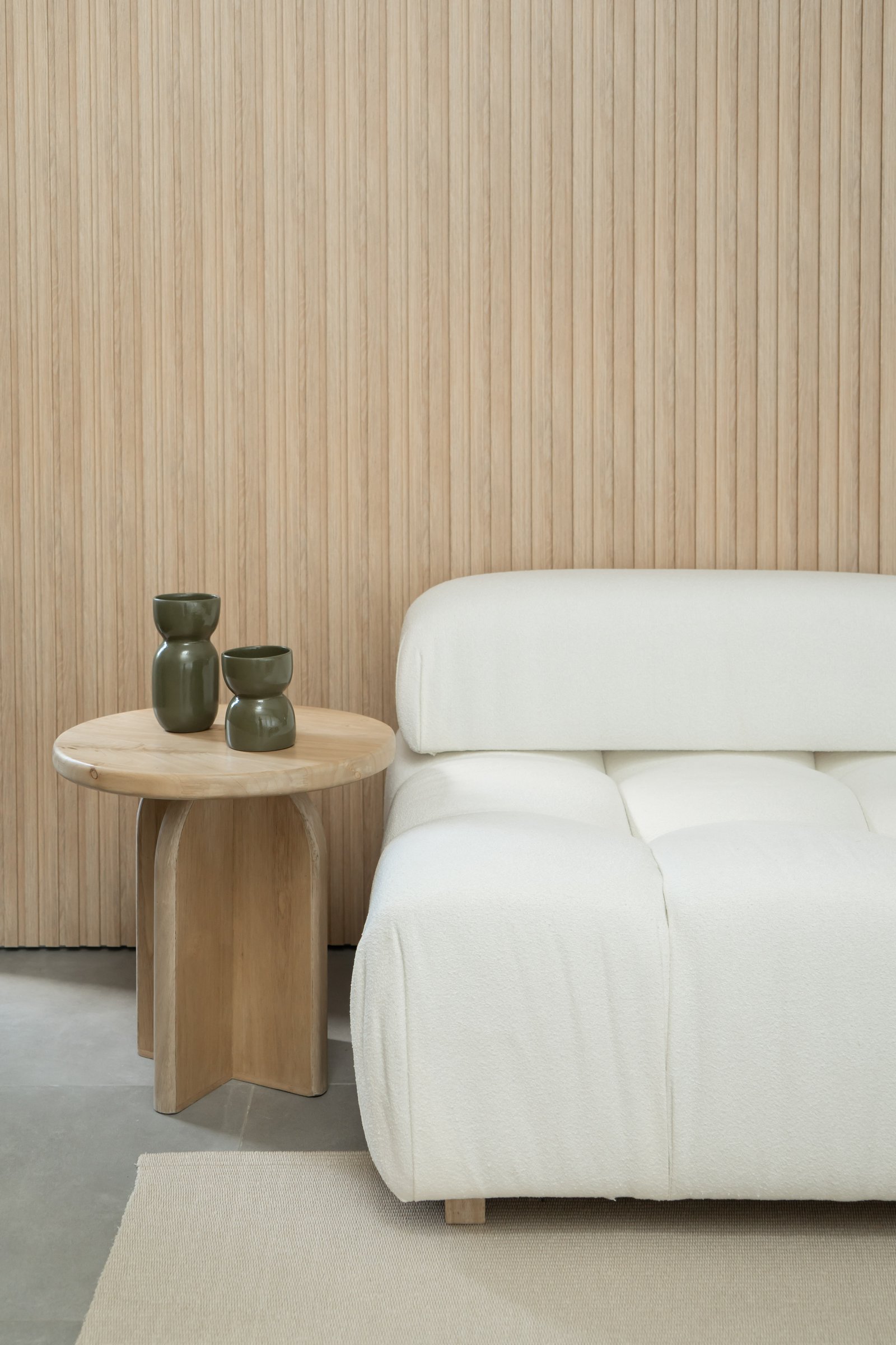 Sofá blanco modular y mesa de madera con vases verdes en sala minimalista — proyecto PROYECTO NAUDIR, por July Acosta Home, en Belén de Escobar