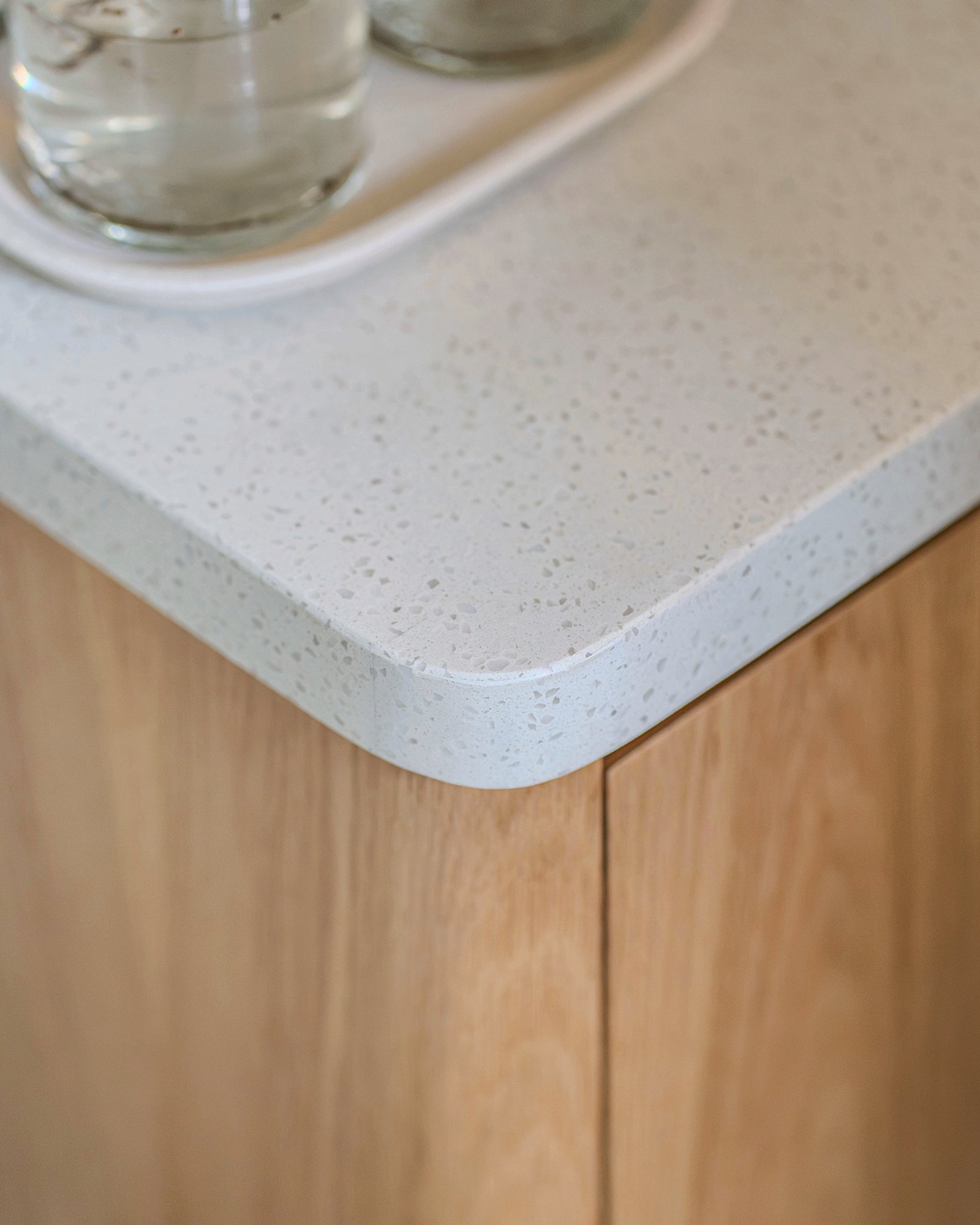 Detalle de encimera blanca con borde redondeado y mueble de madera clara — proyecto Quesada, por Blue Rabbit Design, en Núñez