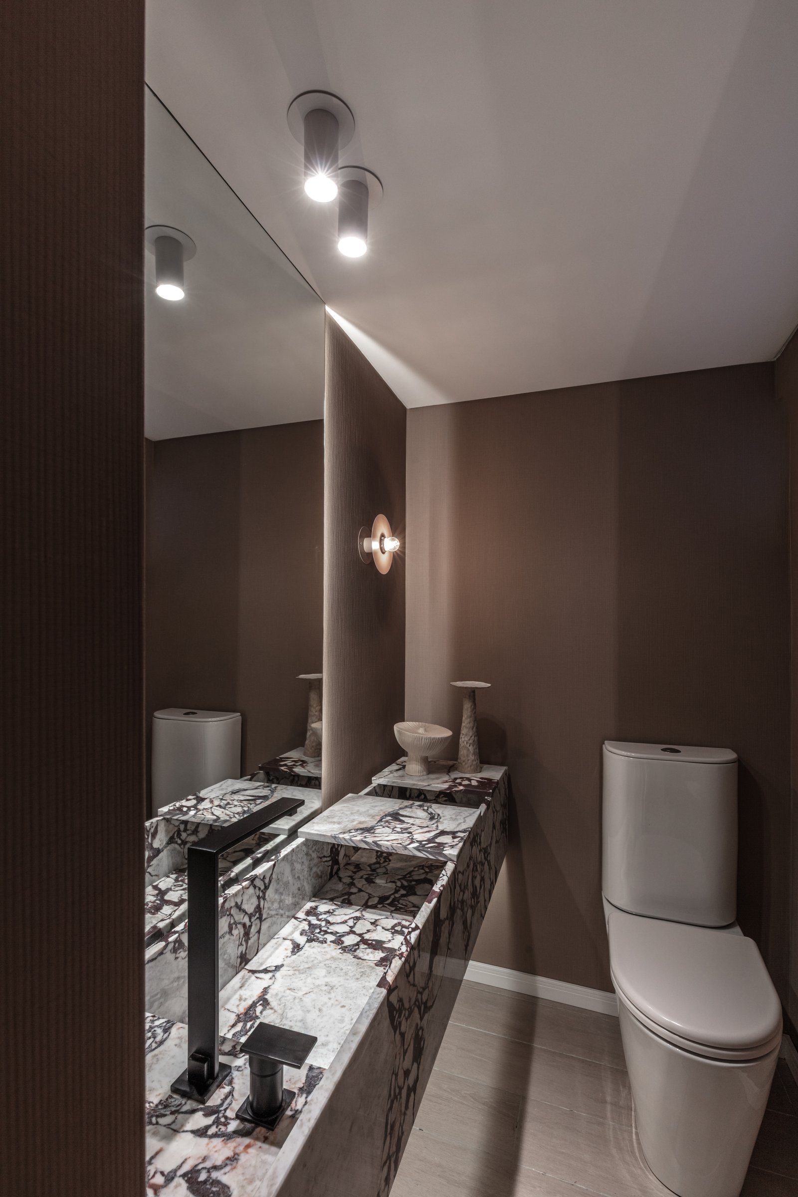 Banheiro moderno com bancada de mármore, torneira preta e iluminação ambiente — projeto Eslovenia | Pied-à-terre | Lucia Quinteros, por Ren Studio, em Cdad. Autónoma de Buenos Aire