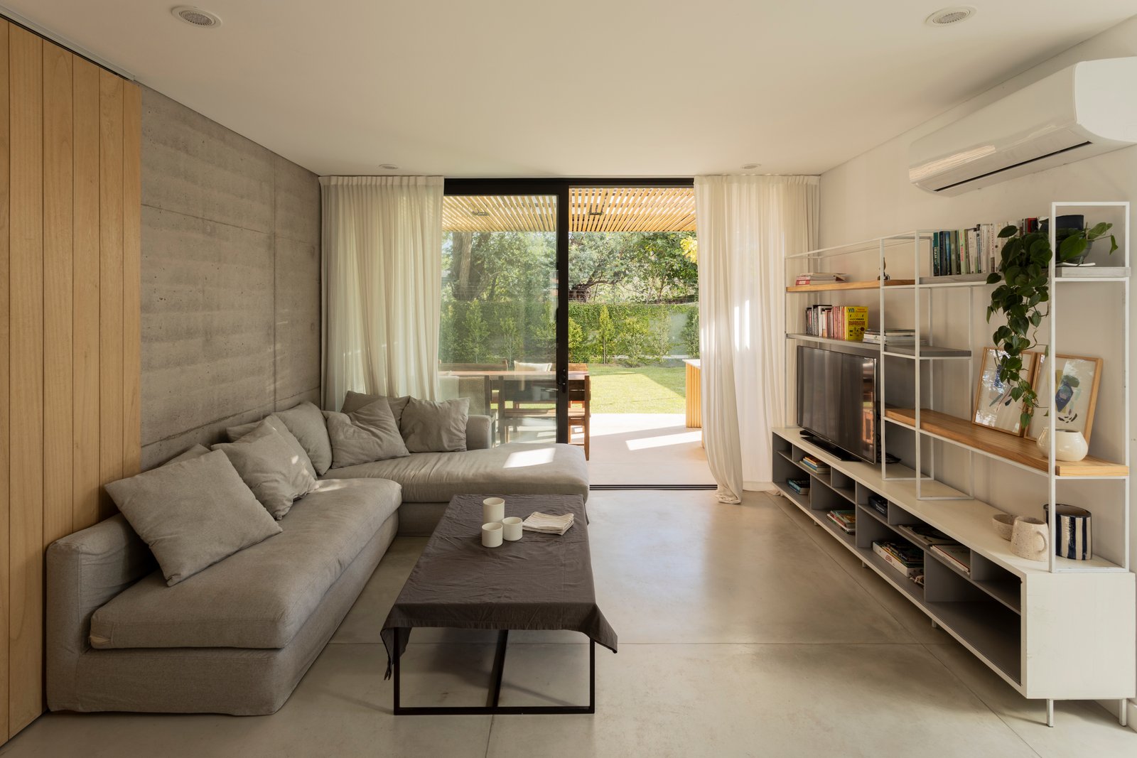 Sala moderna com sofá modular e parede de madeira — projeto CASA CC, por Rastro Estudio, em San Isidro