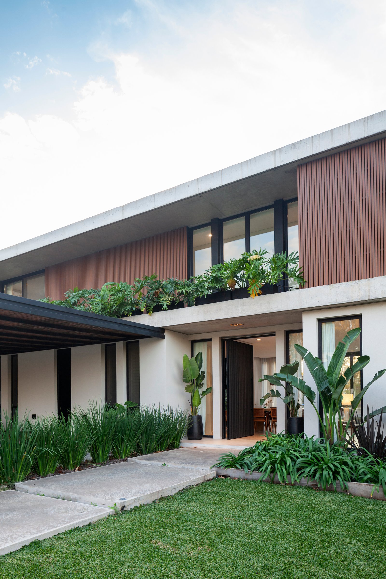 Fachada moderna com revestimento vertical de madeira e concreto — projeto CASA HS143, por A'PRIMA - Arquitectura Sustentable, em km 7.5 Ruta 25
