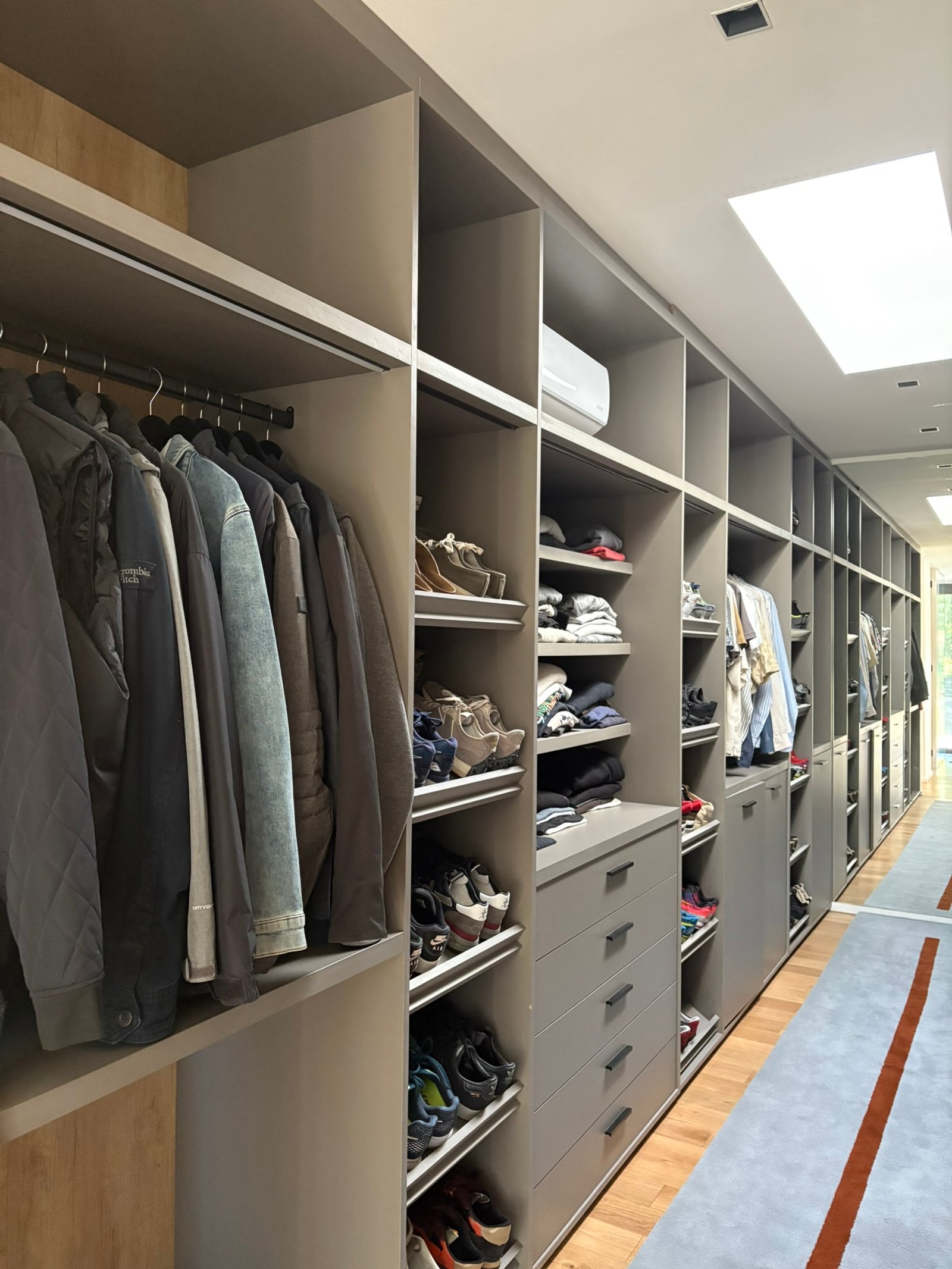 Um closet moderno e espaçoso com prateleiras modulares cinzas e piso de madeira — projeto Peru, por ABEJA CONCEPT, em B1641 Acassuso