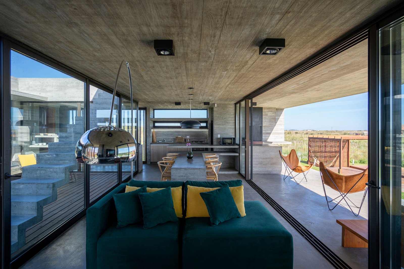 Living moderno con vista al mar y techo de hormigón — proyecto Casa Médanos, por Besonías Almeida arquitectos, en JWRC+MQ