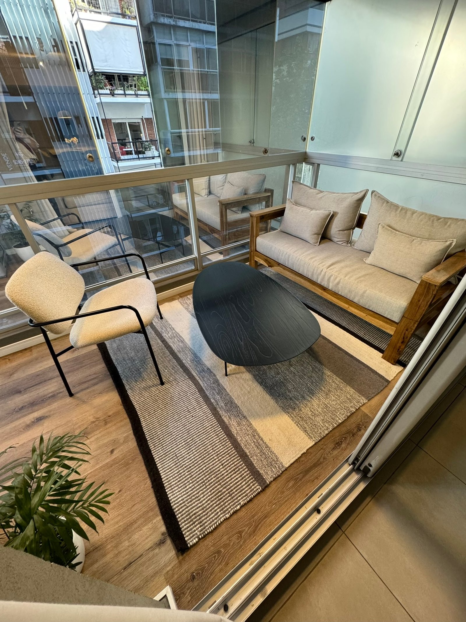 Balcón moderno con sofá beige, mesa de madera y plantas — proyecto Salguero I, por MDBK Arquitectura, en Palermo