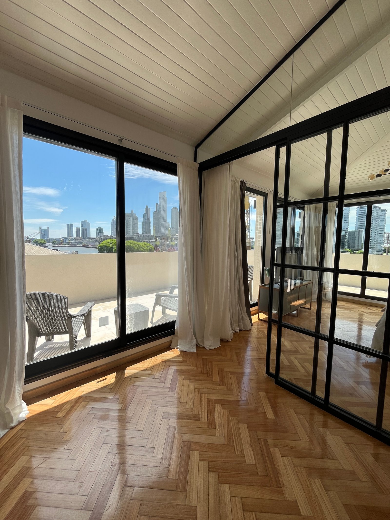 Living moderno con piso de madera y vista a la ciudad — proyecto Departamento Puerto Madero, por Arcucci Arquitectura, en Puerto Madero
