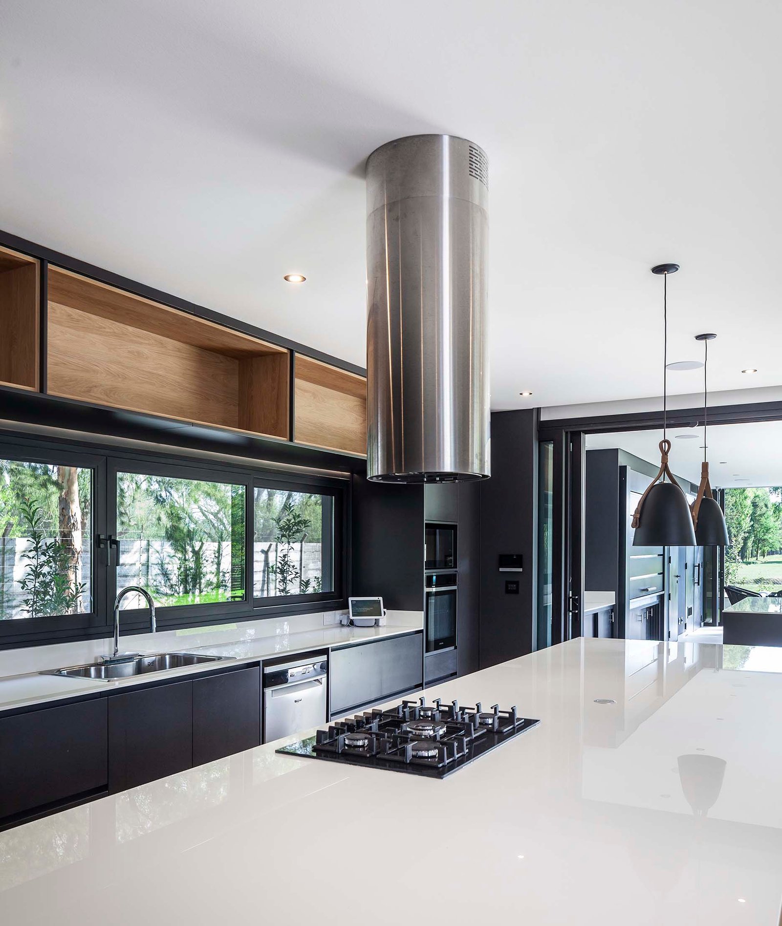 Cozinha moderna com ilha branca, janelas amplas e detalhes em madeira — projeto CASA T199, por A'PRIMA - Arquitectura Sustentable, em Los Robles 5901