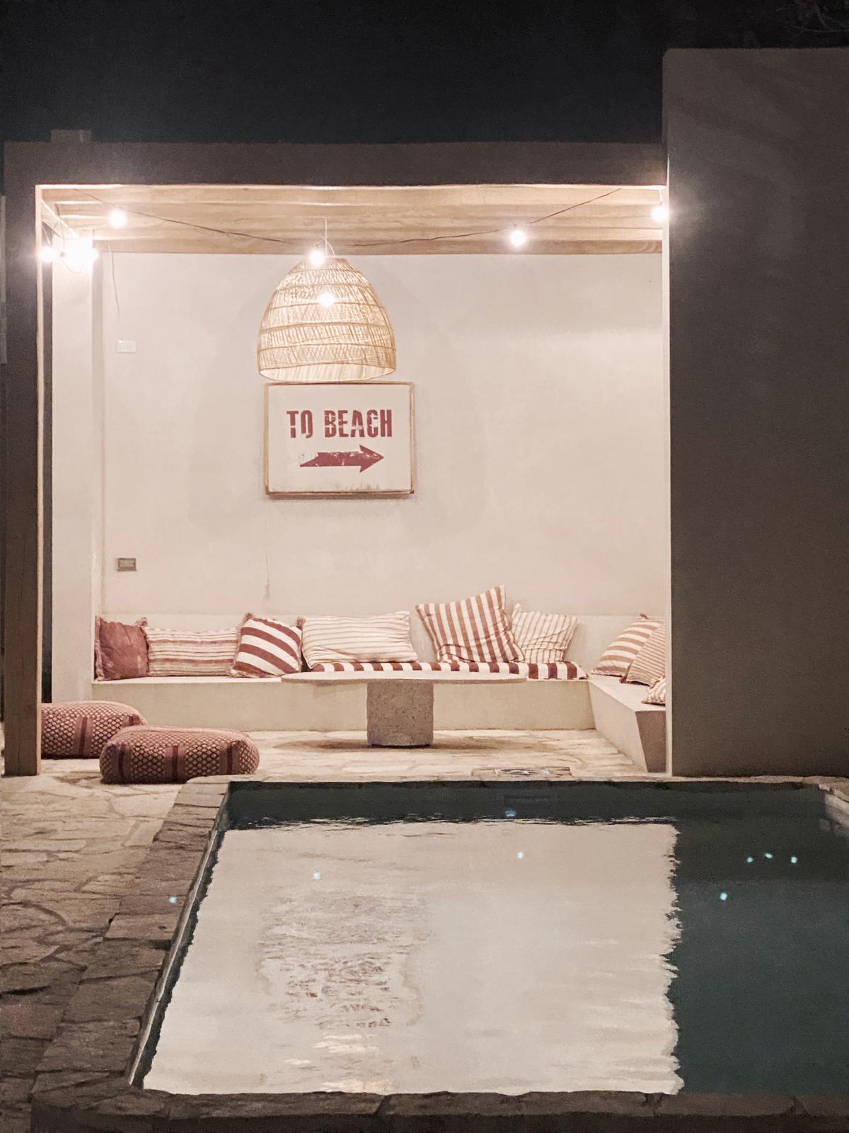 Área de piscina com estilo boho mediterrâneo e iluminação quente — projeto El Refugio, por Grupo Pauta Arquitectura, em Pinamar
