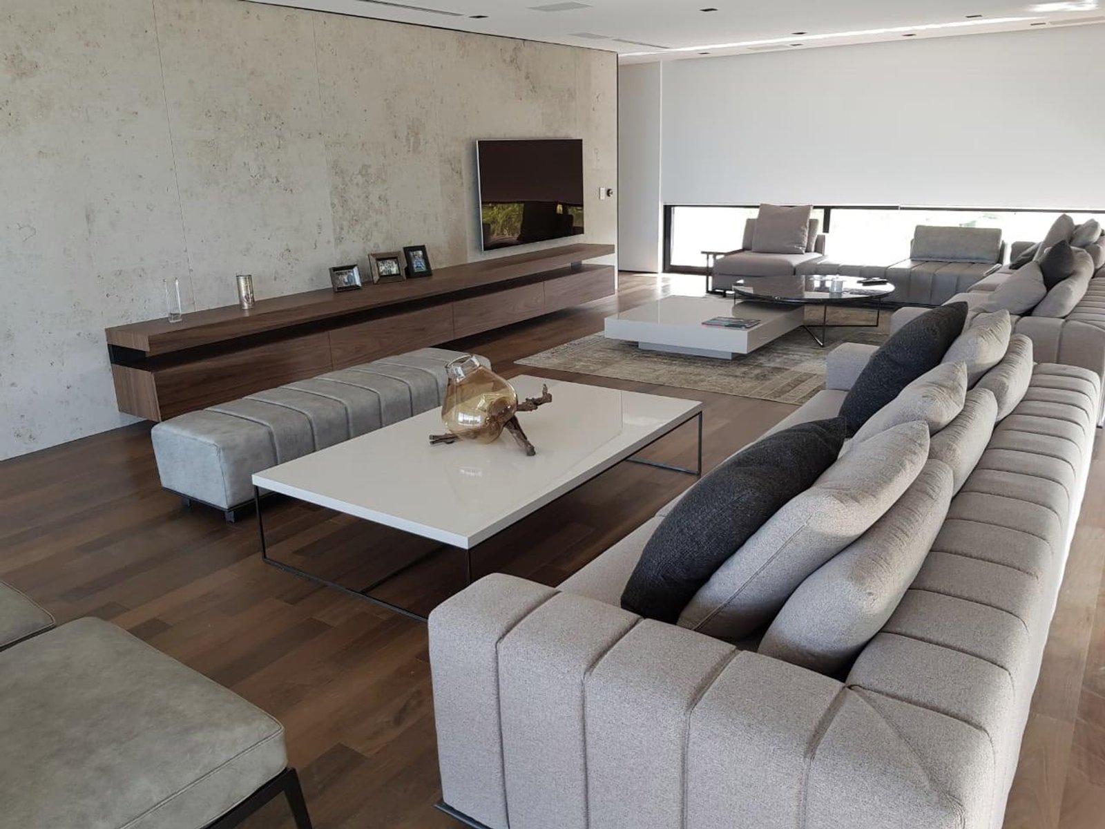 Living moderno con sofá modular y pared de concreto — proyecto Espacios, por BURANI, en Martínez