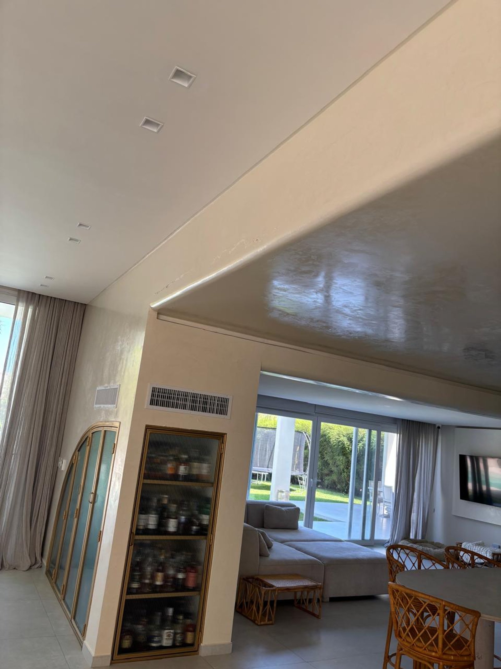 Living moderno con muebles de rattan y grandes ventanales al jardín — proyecto INSTALACIONES , por CLIMA STAR SRL , en Pichincha 167