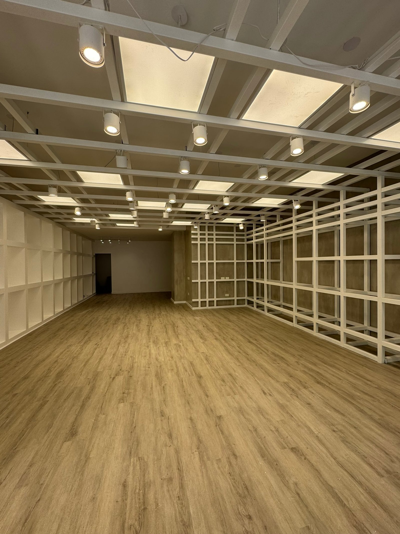 Espaço comercial amplo com prateleiras de grade metálica e iluminação zenital — projeto Leonardo Marroquinería, por MDBK Arquitectura, em Balvanera