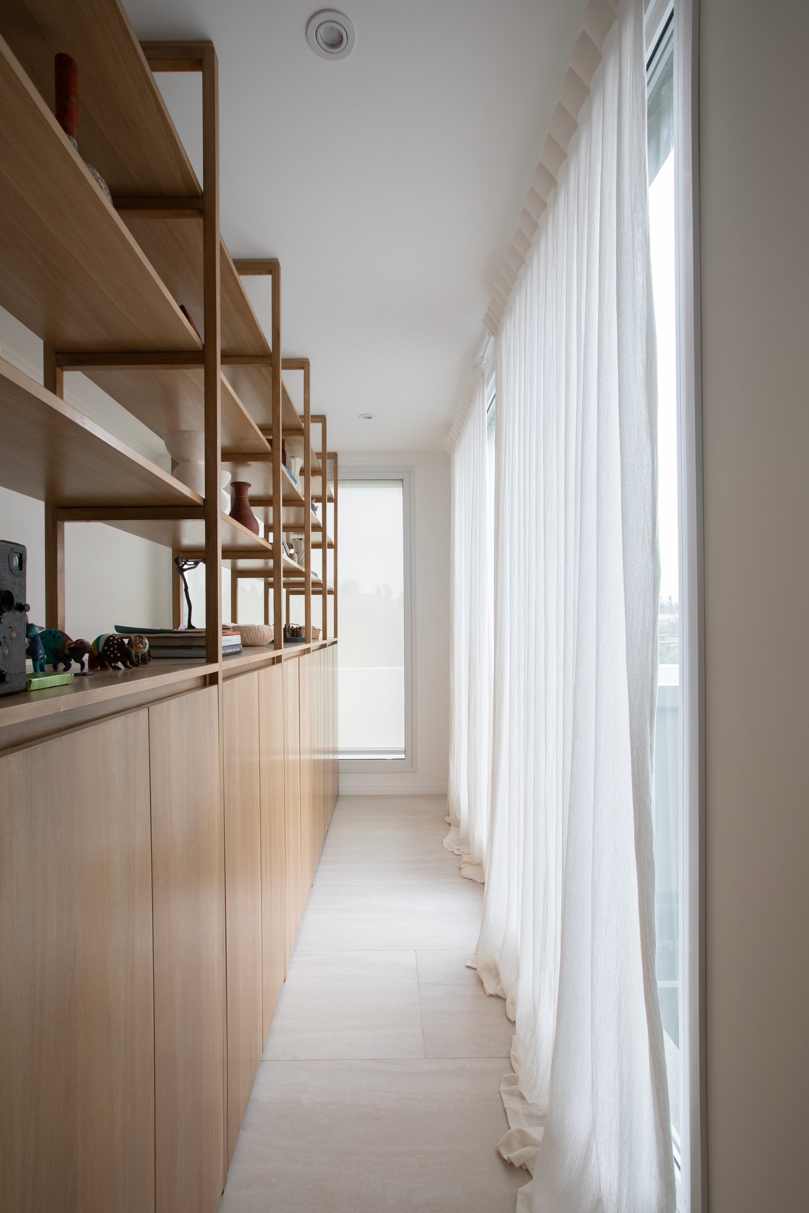 Pasillo con muebles de madera y estanterías abiertas, cortinas blancas — proyecto OBRA EL RETIRO, por ILVA, en Provincia de Buenos Aires
