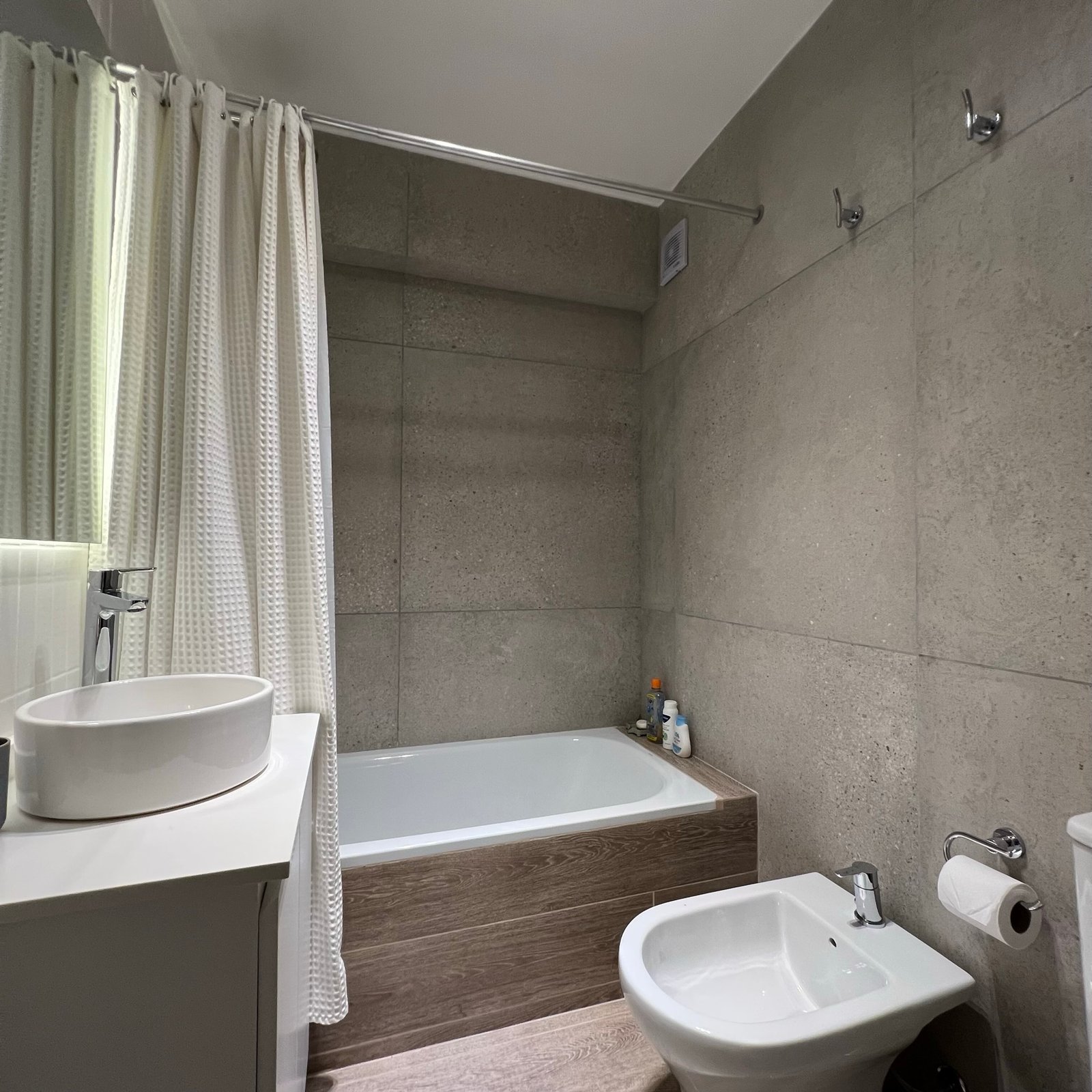 Baño moderno con bañera exenta y revestimiento de piedra gris — proyecto Vera I, por MDBK Arquitectura, en Villa Crespo