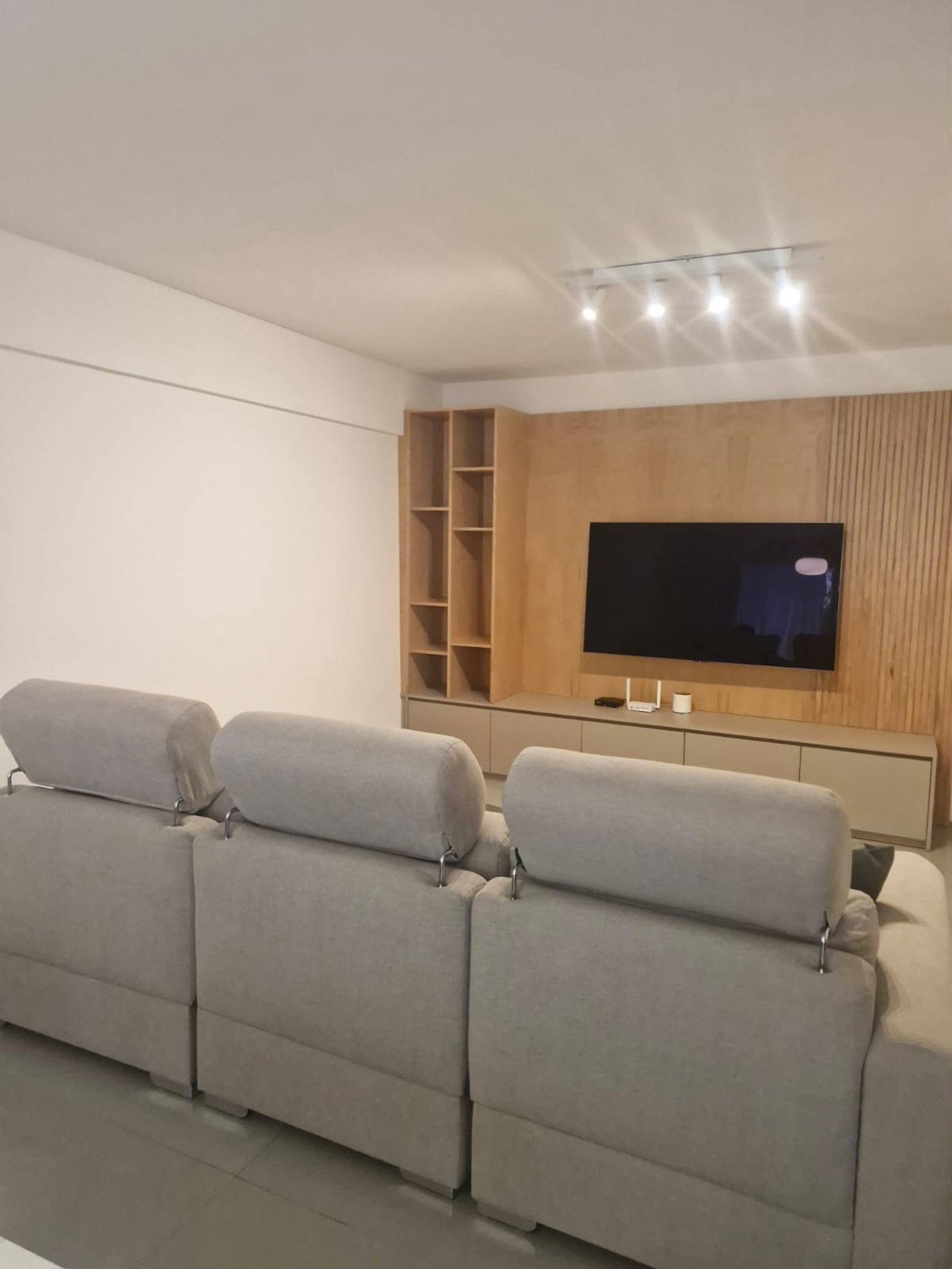 Living moderno con sofá seccional gris y panelado de madera — proyecto Proyecto Andonaegui - Diseño y ejecución integral living, por MJS INTERIOR DESIGNER, en Andonaegui