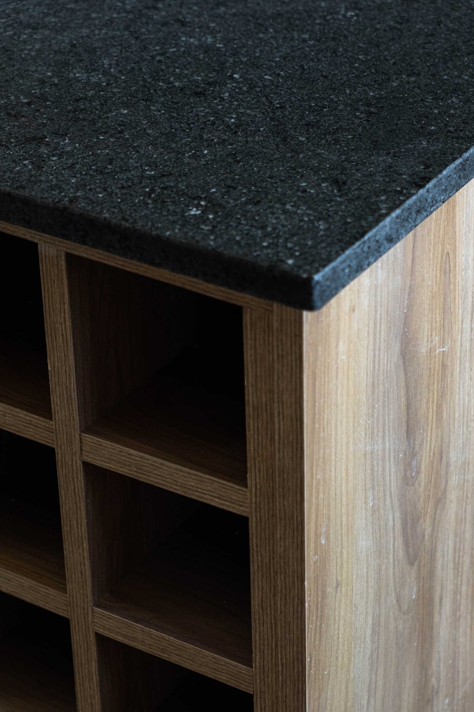Isla de cocina con cubierta de piedra negra y estanterías de madera — proyecto CASA GOLF, por SEDE Arq., en Av. Pereda S/N
