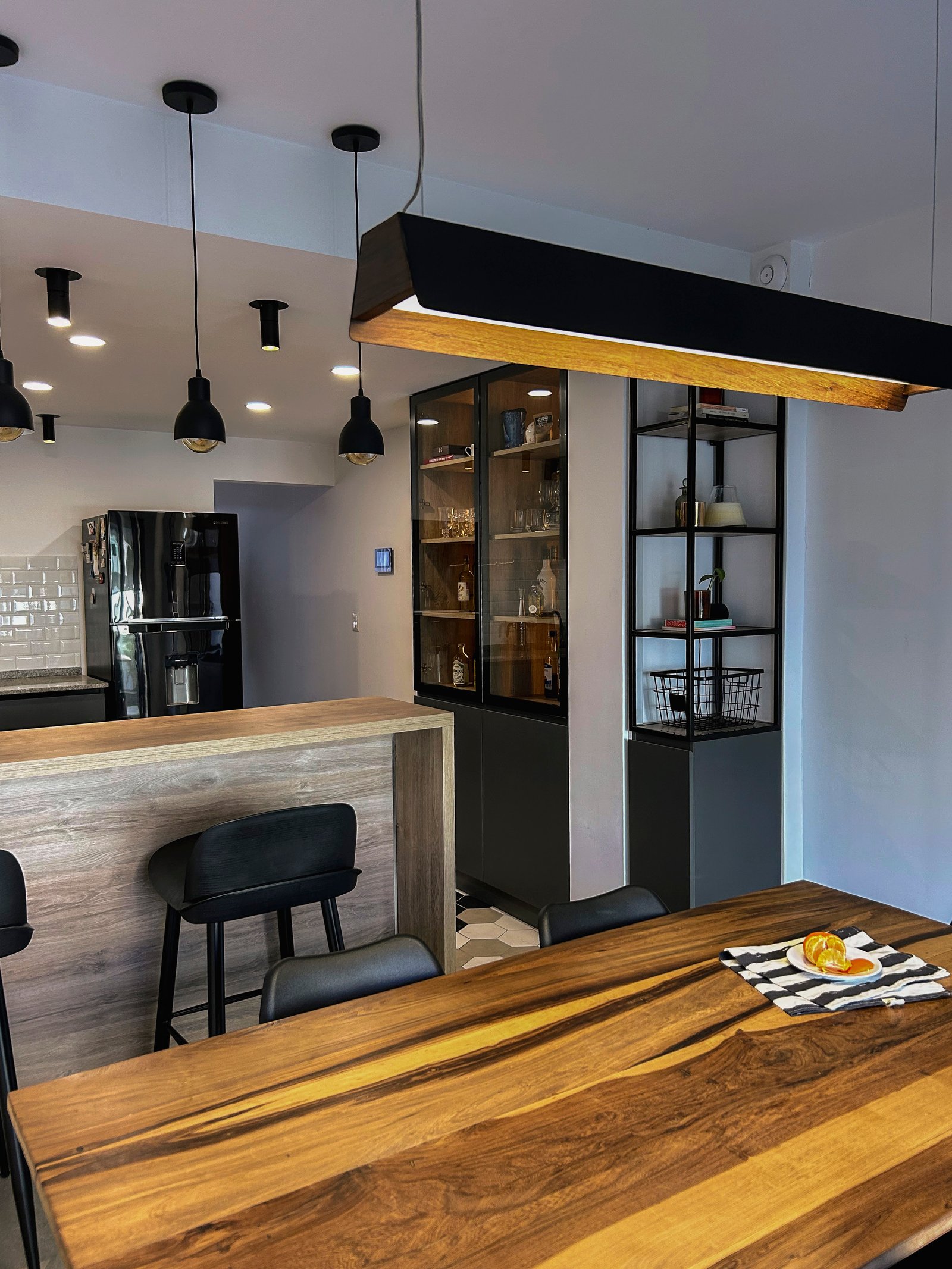 Comedor moderno con mesa de madera, iluminación colgante y cocina integrada — proyecto Vivienda Mari y Lean, por Jeitinho Estudió Creativo, en La Plata
