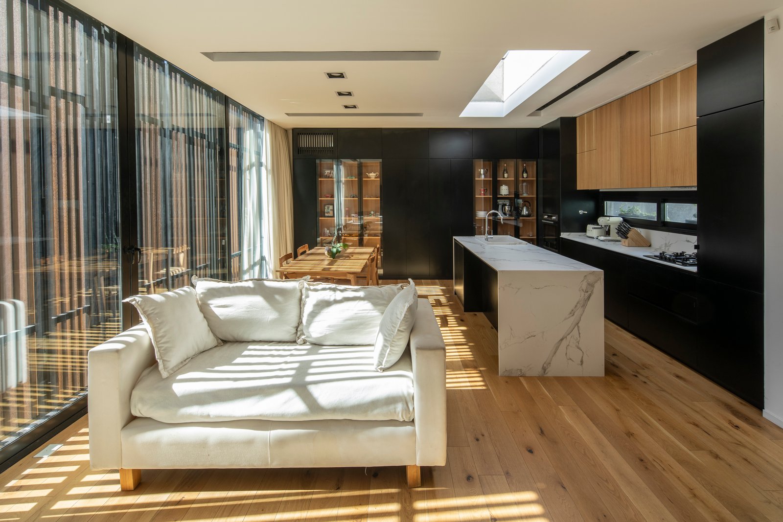 Living moderno integrado con isla de cocina y ventanales amplios — proyecto Casa MECHA, por Grupo CRBN, en B1712 Castelar