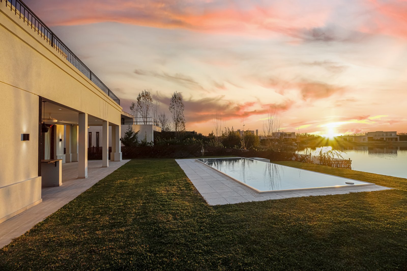 Fachada moderna junto a piscina con atardecer sobre laguna — proyecto Casa SS182, por EZ architects, en M3CV+6H