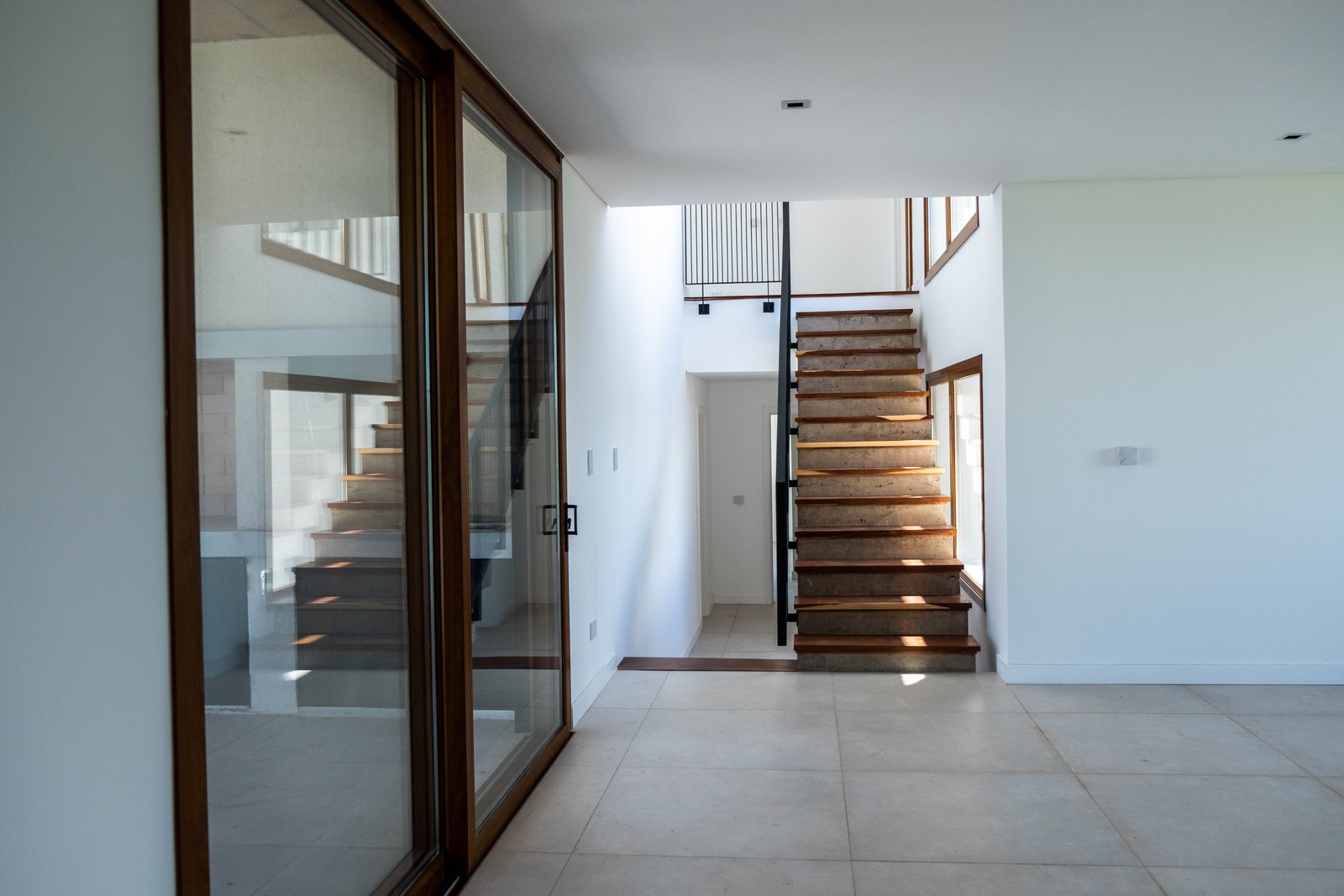 Escalera flotante moderna con grandes ventanales y detalles en madera — proyecto CASA GOLF, por SEDE Arq., en Av. Pereda S/N