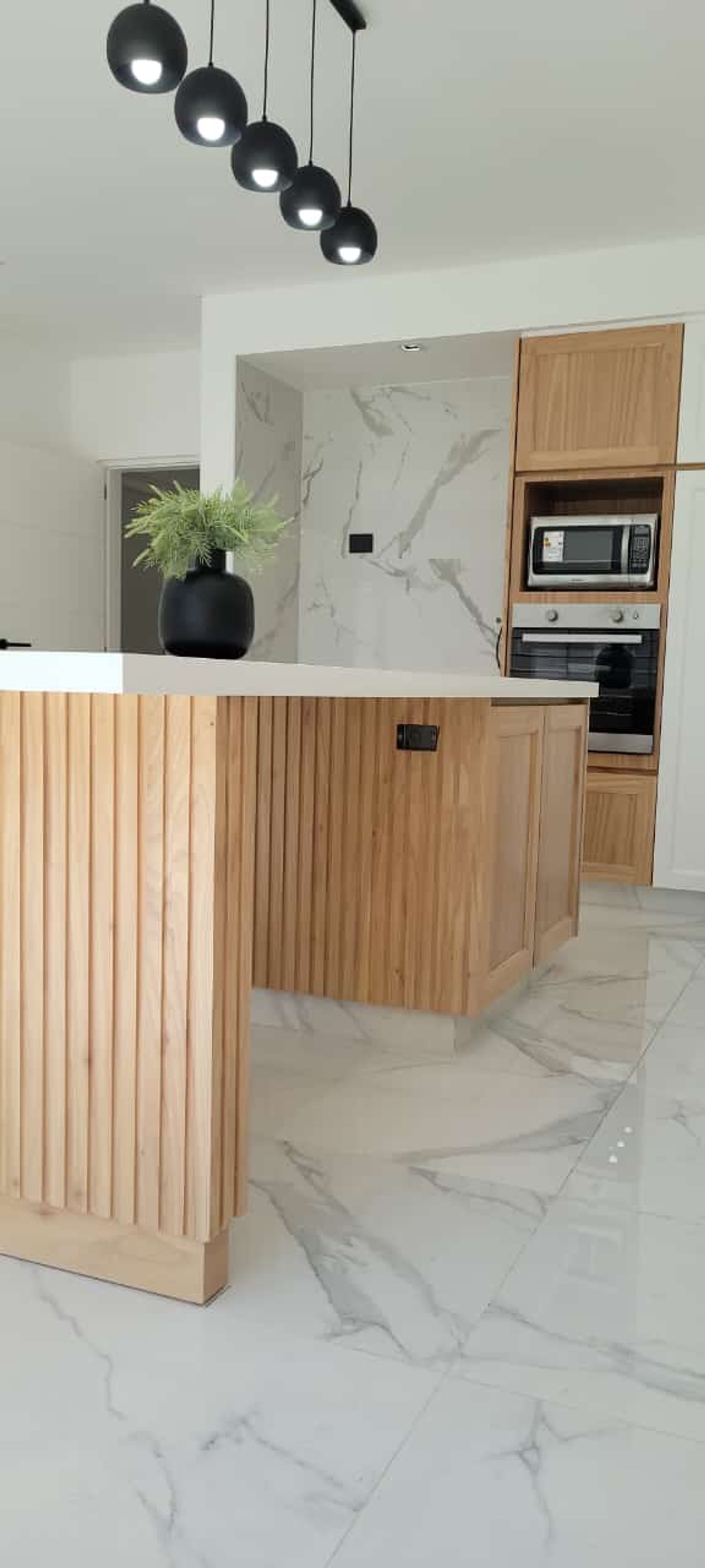 Cocina moderna con isla de listones de madera y suelo de mármol — proyecto Ramos, por Licefe Carpentry SRL, en B1704 Ramos Mejía