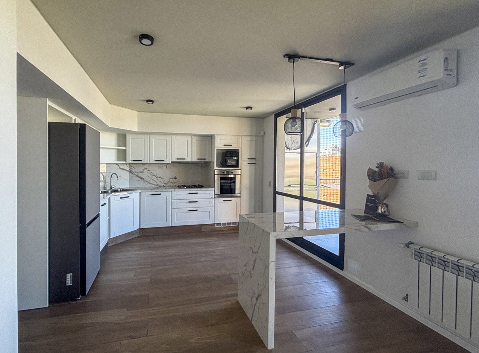 Cocina moderna abierta con isla grande y luz natural — proyecto EDFICIO DM60, por DIB OBRIST Arquitectas, en Rosario