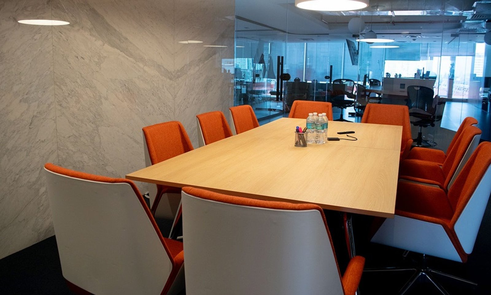 Sala de reuniões moderna com parede de mármore e cadeiras laranjas — projeto oficinas voicess// polanco / atlantico arqs, por atlantico arqs, em Polanco