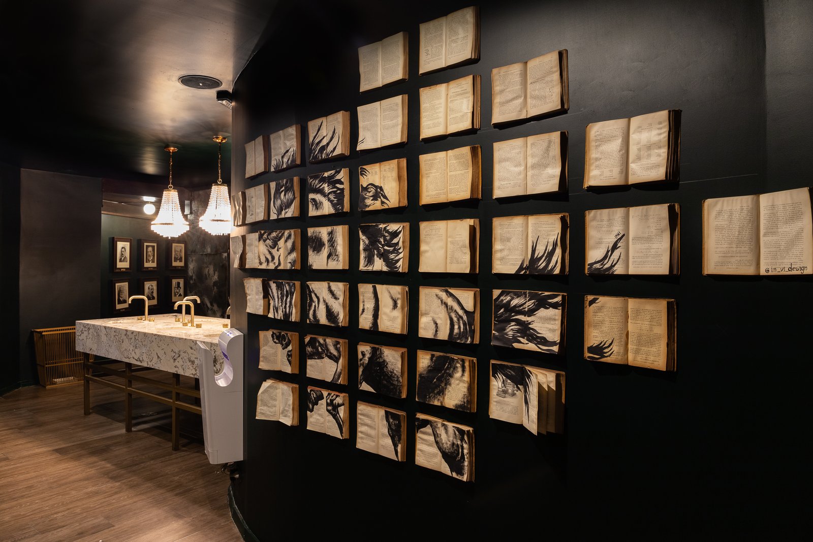 Instalación artística en pared con páginas enmarcadas, iluminación cálida y detalles en madera oscura — proyecto PRESIDENTE BAR HIPODROMO, por AB ARQUITECTURA, en San Isidro