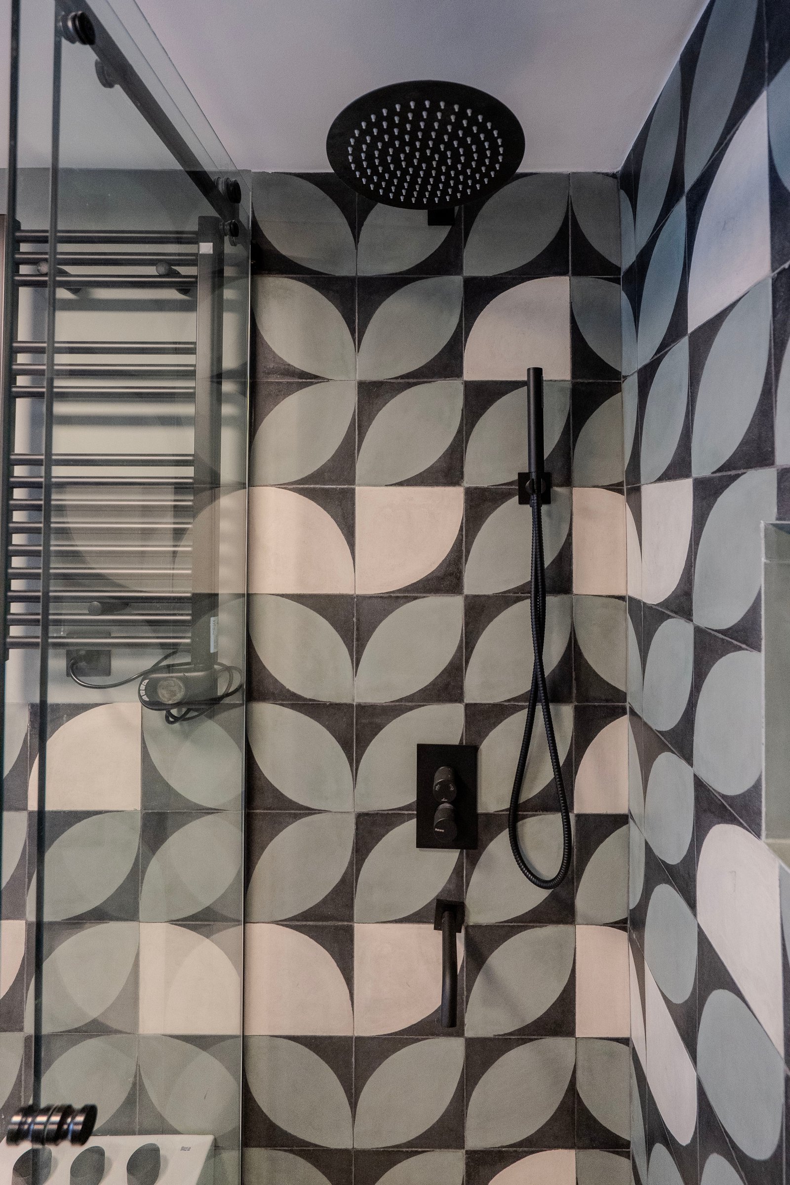 Baño moderno con azulejos geométricos y accesorios negros — proyecto Al Río - Baño, por Blue Rabbit Design, en Vicente López