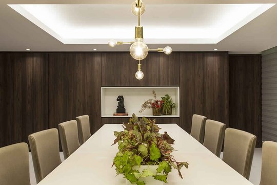 Comedor contemporáneo con mesa blanca, sillas beige y pared madera oscura — proyecto Jantar, por Xico Diniz