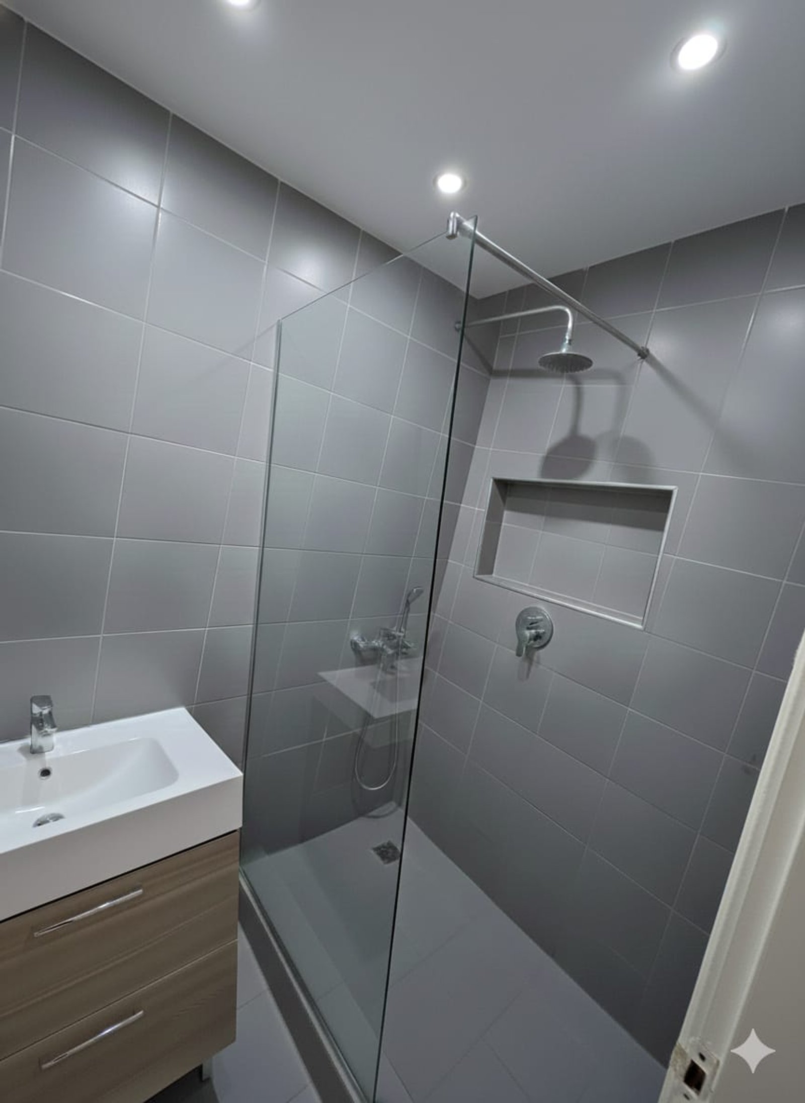 Baño moderno con ducha de vidrio y lavabo sobre mueble de madera — proyecto Remodelación Baño , por pablokunica2009, en San Fernando