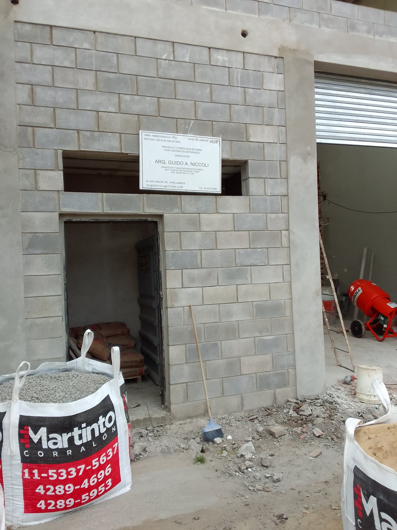 Fachada de edificio en construcción con materiales apilados y maquinaria — proyecto Deposito en Avellaneda, por Arquitecto Guido Niccoli, en B1872 Sarandí