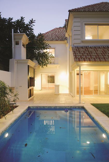 Casa contemporánea blanca con pileta y patio iluminado al atardecer — proyecto Reformas Urbanas, por Ciba Arquitectura