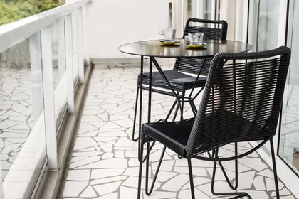 terraza con mesa y sillas de mimbre negro — proyecto La Pampa, por Estudio Basa, en CABA