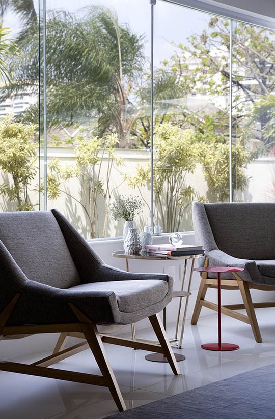 Dos sillones grises con ventanal y plantas naturales al fondo — proyecto Casa Blue House, por Amanda Miranda