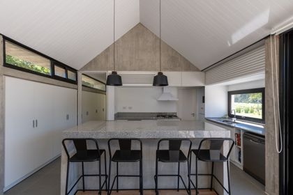 Cocina moderna con isla, techo a dos aguas y pendientes negras — proyecto Casa TT, por Grupo Studio, en Villa Allende