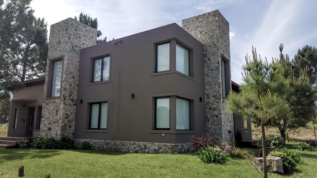Casa moderna con acentos de piedra y grandes ventanales — proyecto Vivienda Multifamiliar en Las Gaviotas, por Estudio Schifano, en Canning