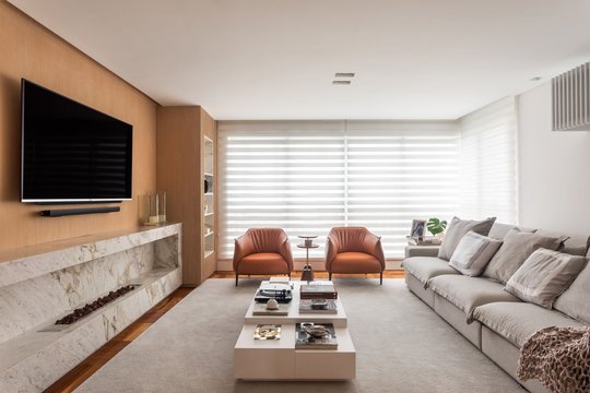 living moderno con TV marmol sillones terracota y sofá gris — proyecto Apartamento BP, por GabrielaCasagrande Arquitetura