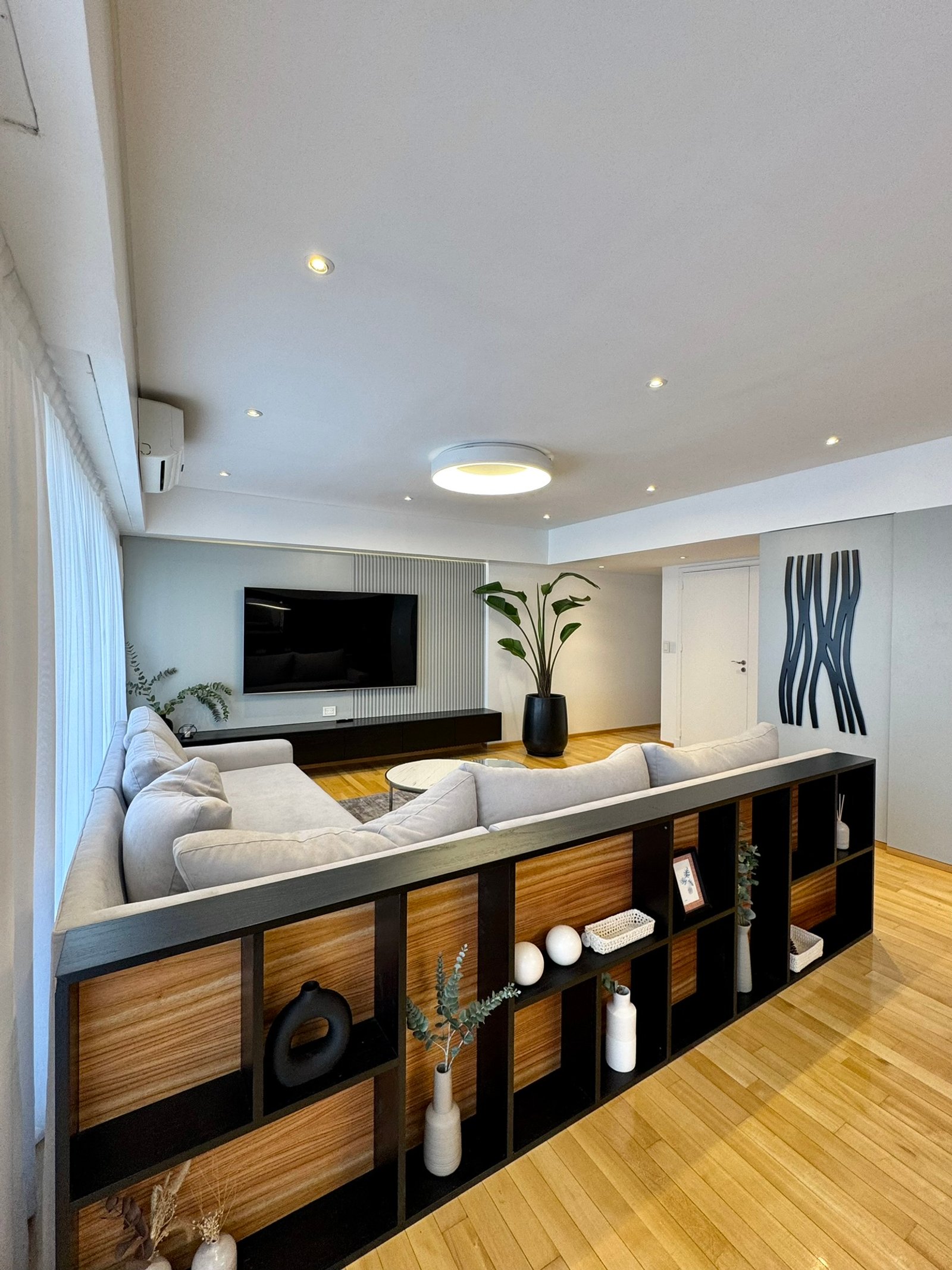 Living moderno con sofá seccional gris y estanterías integradas de madera — proyecto Mendoza, por MDBK Arquitectura, en Belgrano