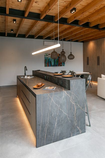 Cocina moderna con isla de mármol gris y techo de madera rústica — proyecto Casa Oroño, por Estudio Plats, en Buenos Aires